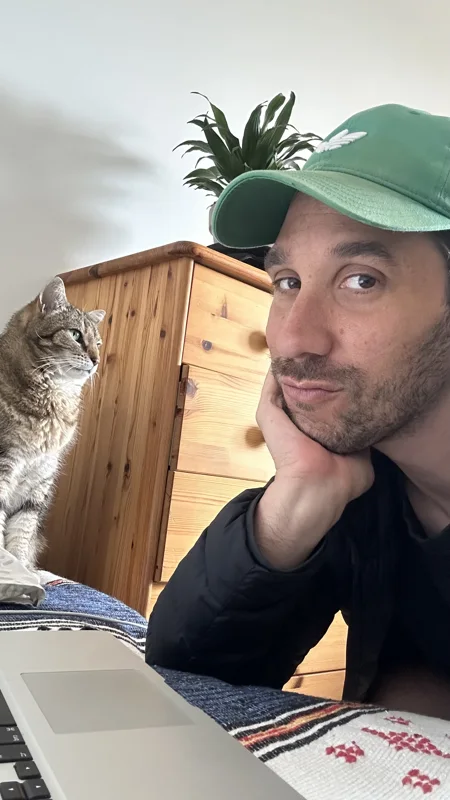 Ma photo de départ&nbsp;: selfie, la joue sur la main, casquette verte, un chat derrière moi