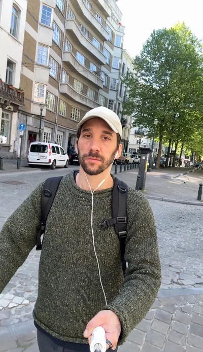 Ma photo de départ : selfie à la perche dans la rue, pull vert, sac à dos, écouteurs
